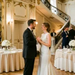 Couple élégant lors d'une réception de mariage dans un salon parisien orné de dorures et de fleurs blanches